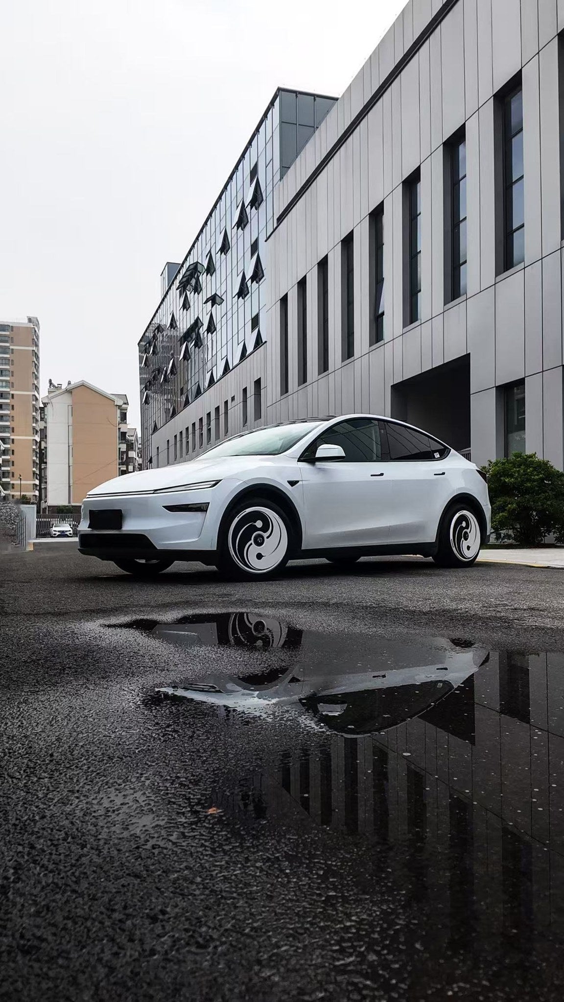 Yin Yang aero wheel covers on a white Tesla Model Y, street setting