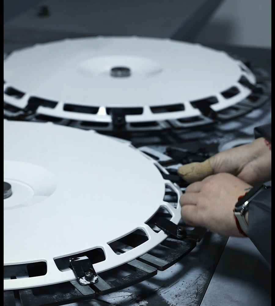 A blank wheel cover being loaded into its jig
