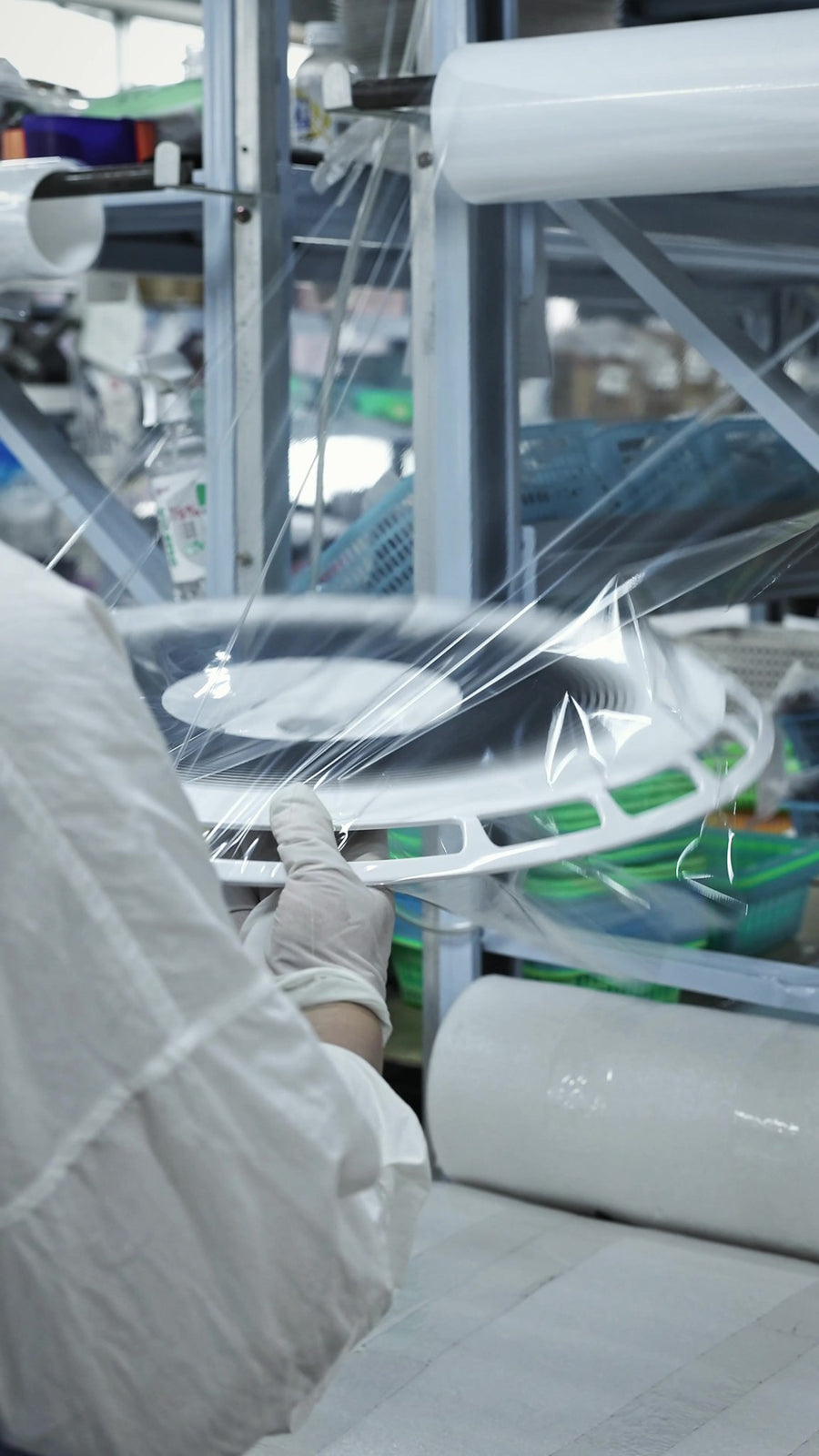A wheel cover being film-wrapped by hand before boxing