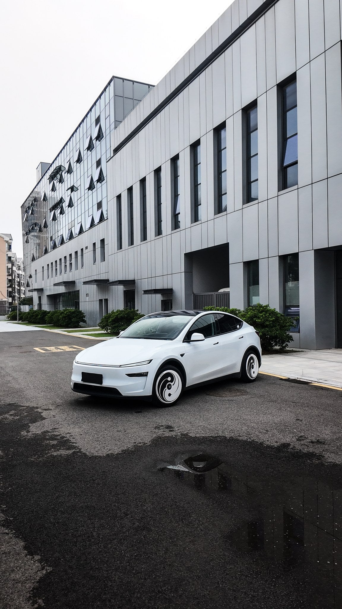 Tesla Model Y in white with Yin Yang aero wheel covers, front three-quarter